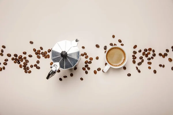 Vista superior de la cafetera de metal, granos de café y taza sobre fondo beige - foto de stock
