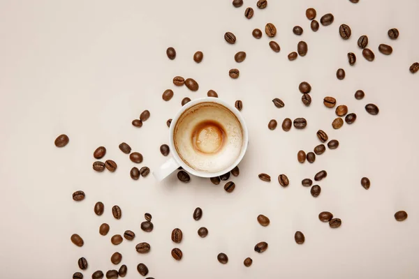Vue du dessus de tasse à café avec mousse sur fond beige avec grains de café — Photo de stock