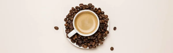 Vue du dessus de la tasse de café sur la soucoupe avec des grains sur fond beige, panoramique — Photo de stock