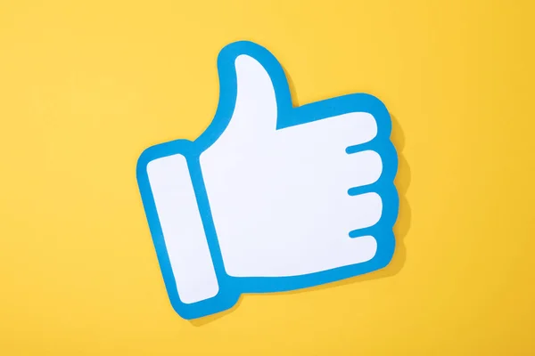 Top view of white paper hand with thumb up on yellow background — Stock Photo