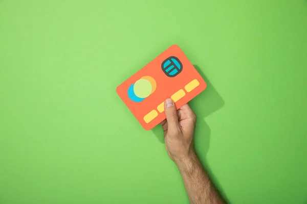 Cropped view of man holding red paper icon of credit card on green — Stock Photo