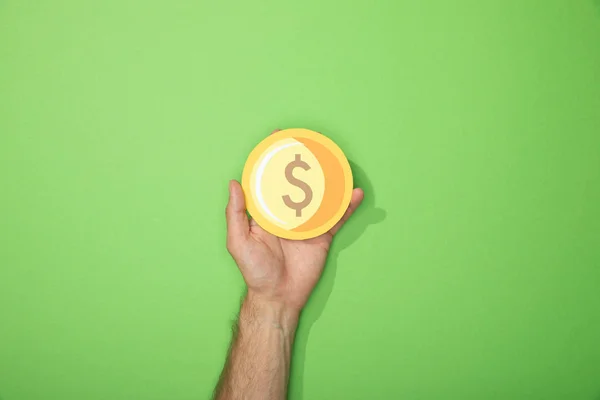 Cropped view of man holding paper yellow coin on green — Stock Photo