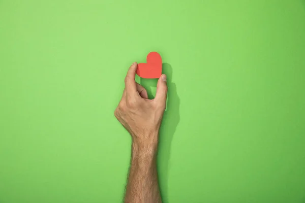 Cropped view of man holding paper heart on green — Stock Photo