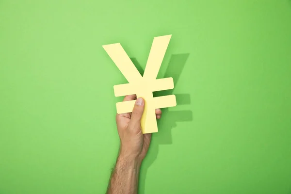 Cropped view of man holding yellow yen currency sign on green — Stock Photo