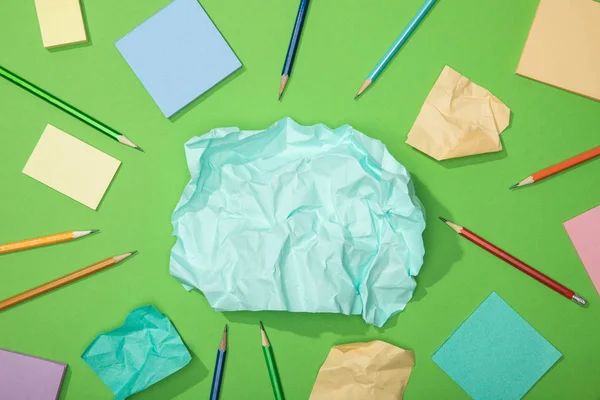 Vista superior de pedaços dispersos de papel amassado perto de lápis em verde — Fotografia de Stock