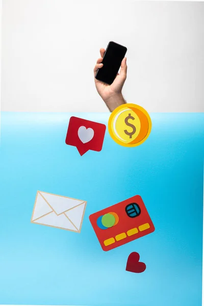 Cropped view of man holding smartphone and paper icons falling down — Stock Photo