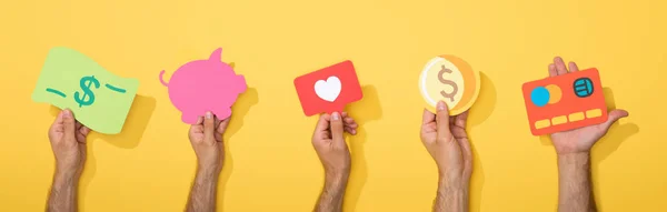 Panoramic shot of men holding colorful paper icons on yellow — Stock Photo