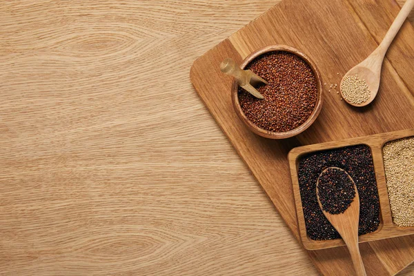 Vista superior de la quinua blanca, negra y roja en cuencos de madera sobre tabla de cortar - foto de stock