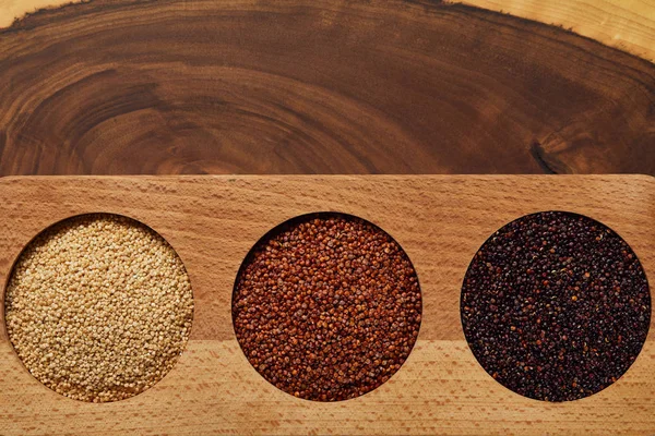 Top view of white, black and red quinoa in wooden round bowls — Stock Photo