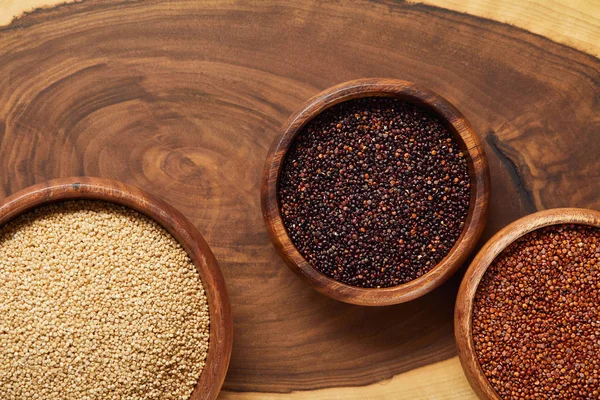 Vue de dessus du quinoa blanc, noir et rouge dans des bols en bois — Photo de stock