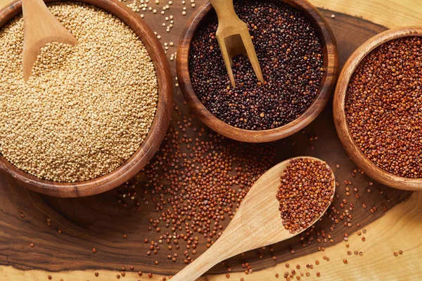 Vista de perto de sementes de quinoa brancas, pretas e vermelhas em tigelas de madeira — Fotografia de Stock