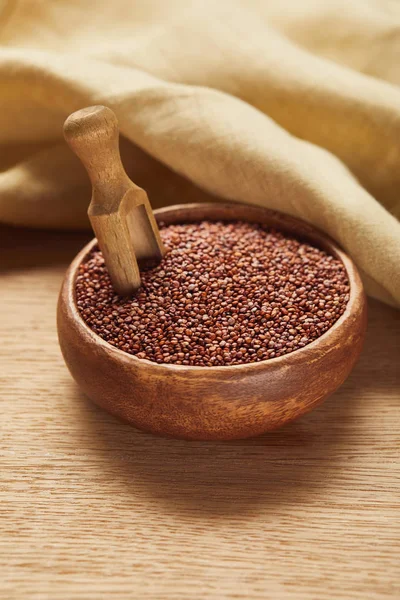 Red quinoa in wooden bowl with spatula near beige napkin — Stock Photo