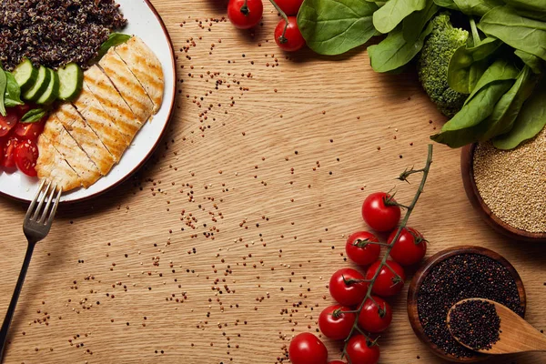 Vista dall'alto della quinoa cotta con petto di pollo alla griglia e verdure su piatto bianco sul tavolo di legno — Foto stock