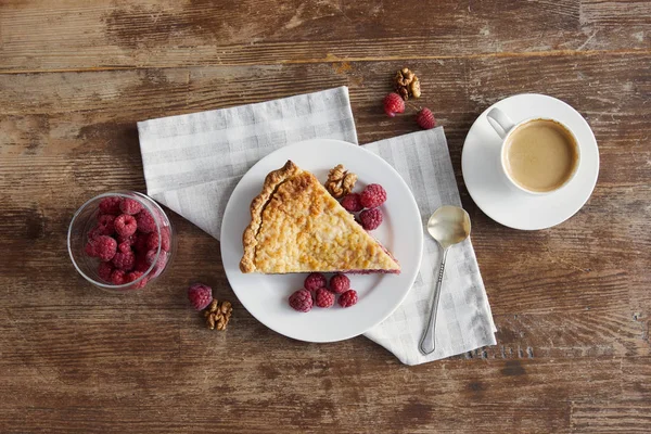 Blick von oben auf das servierte Frühstück mit Stück Kuchen, Himbeeren und Tasse Kaffee — Stockfoto