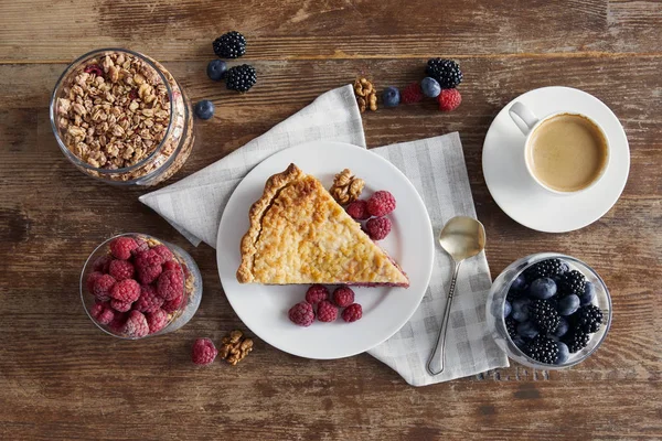 Vista superior del desayuno servido con trozo de pastel, frambuesas, copos de avena y taza de café - foto de stock