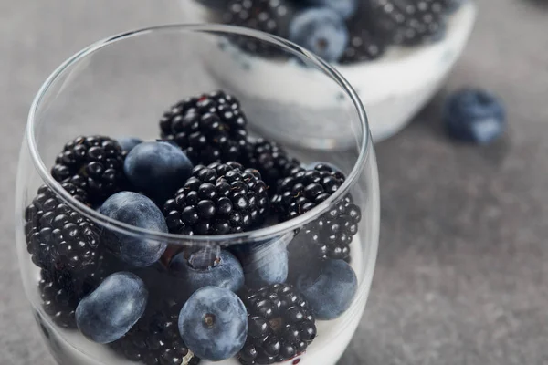 Foco seletivo de iogurte saboroso com sementes de chia, mirtilos e amoras-pretas em copos — Fotografia de Stock