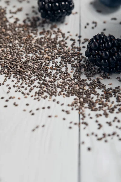 Close up view of scattered chia seeds and blackberries on white wooden table — Stock Photo