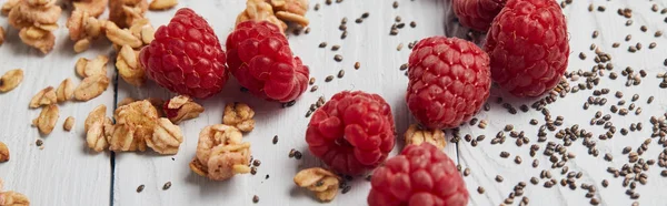 Panoramic shot of scattered raspberries, chia seeds and oat flakes on white wooden table — Stock Photo
