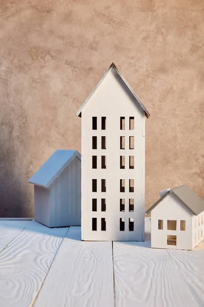 Maisons modèles sur table en bois blanc près du mur texturé, concept immobilier — Photo de stock