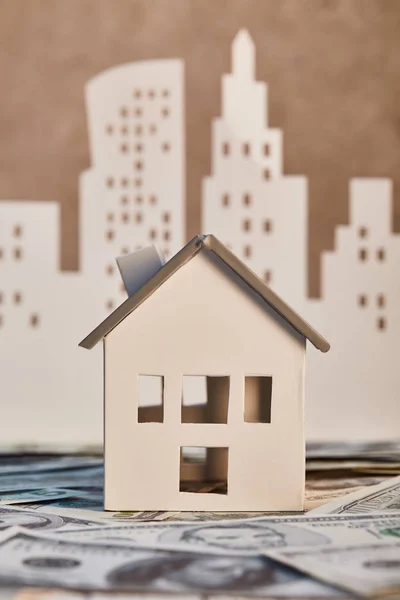 House model on dollar banknotes with white paper city on background, real estate concept — Stock Photo