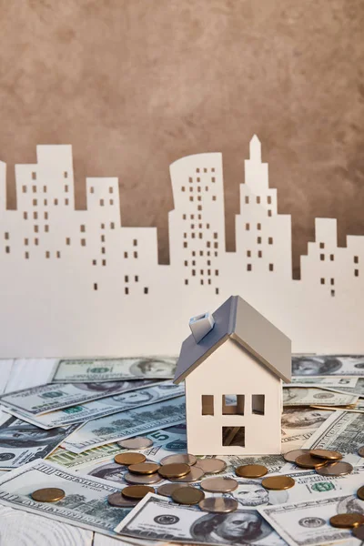 House model on dollar banknotes near coins and paper city on background, real estate concept — Stock Photo