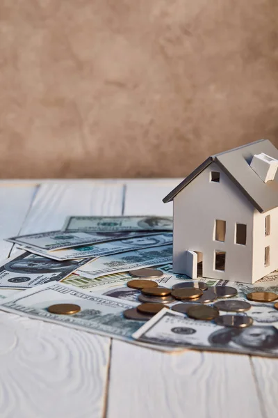 Modelo de casa en billetes de dólar y monedas en mesa de madera, concepto de bienes raíces - foto de stock