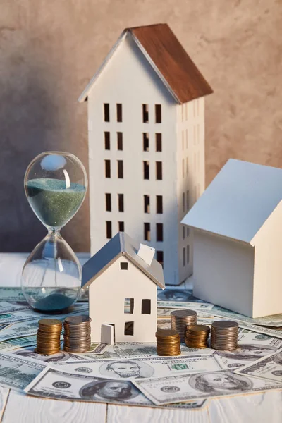 Häuser Modelle und Sanduhr auf Dollarnoten und -münzen, Immobilienkonzept — Stockfoto