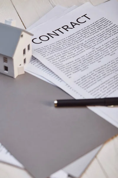 Modelo de casa en mesa de madera blanca cerca de contrato y pluma, concepto de bienes raíces - foto de stock