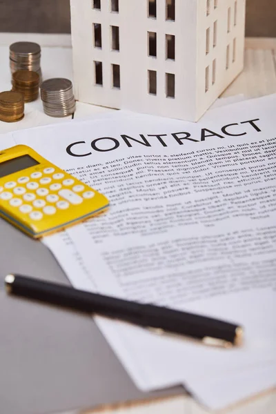 Close up view of house model, coins, yellow calculator near contract with pen, real estate concept — Stock Photo