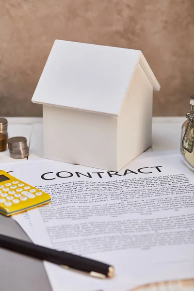 Modelo da casa, moedas, calculadora perto do contrato e da caixa de dinheiro, conceito imobiliário — Fotografia de Stock