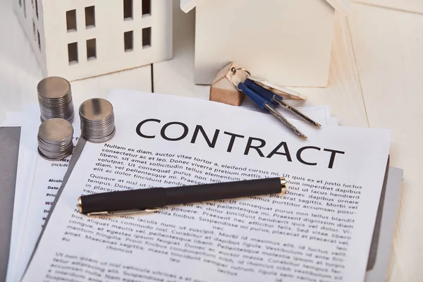 Houses models on white wooden table with contract, pen, keys and coins, real estate concept — Stock Photo