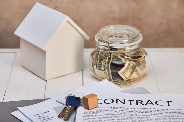 Hausmodell auf weißem Holztisch neben Spardose, Schlüssel und Vertrag, Immobilienkonzept — Stockfoto