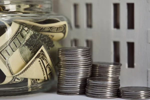 Close up view of house model near silver coins and dollar banknotes in moneybox, real estate concept — Stock Photo