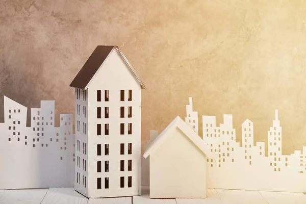 Houses models on white wooden table near white paper cut city in sunlight, real estate concept — Stock Photo