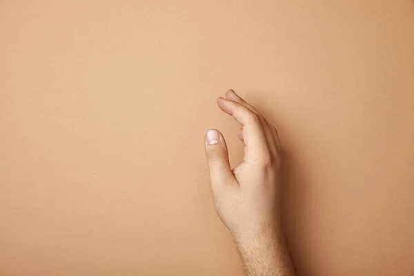 Vista recortada de la mano masculina sobre fondo beige con espacio de copia - foto de stock