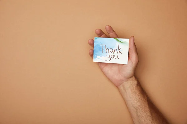 Cropped view of man holding greeting card with thank you lettering on blue background — Stock Photo