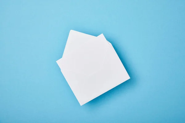 Sobre con tarjeta blanca en blanco sobre fondo azul - foto de stock