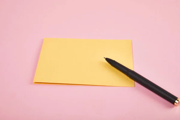 Gelber Umschlag mit Stift auf rosa Hintergrund — Stockfoto