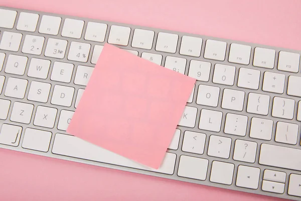 Vue du haut de la note collante rose vide sur clavier d'ordinateur portable sur fond rose — Photo de stock