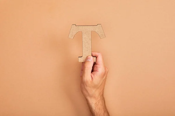 Cropped view of man holding paper cut letter T on beige background — Stock Photo