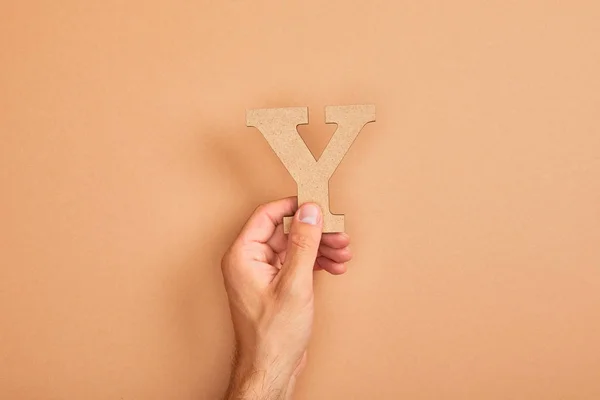 Partial view of man holding paper cut letter Y on beige background — Stock Photo