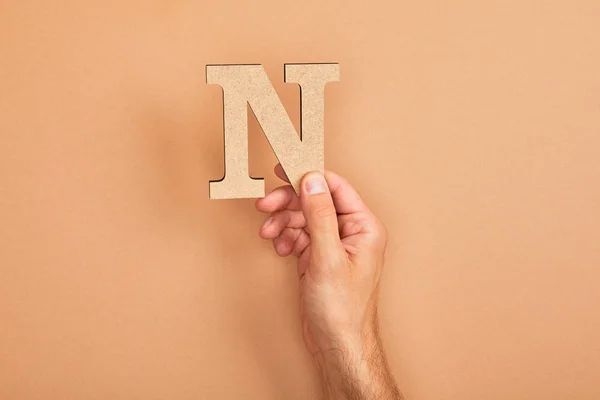 Cropped view of man holding paper cut letter N on beige background — Stock Photo