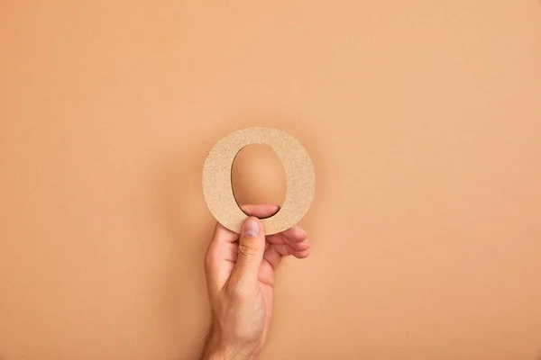 Vista cortada do homem segurando papel cortado letra O no fundo bege — Fotografia de Stock