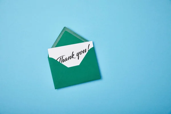 Green envelope and white card with thank you letting on blue background — Stock Photo