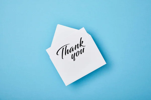 Envelope with thank you lettering on white card on blue background — Stock Photo