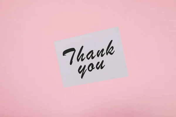 Top view of white card with thank you inscription on pink background — Stock Photo