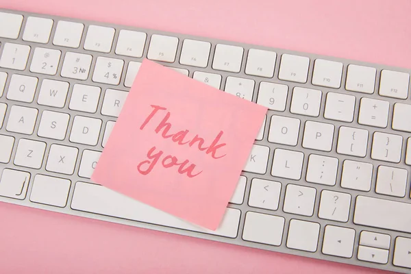 Top view of pink sticky note with thank you words on laptop keyboard on pink background — Stock Photo