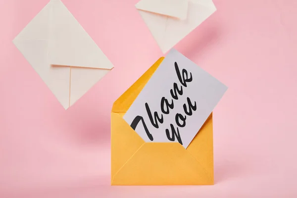 Envelope amarelo com letras de agradecimento no cartão branco perto de letras no fundo rosa — Fotografia de Stock