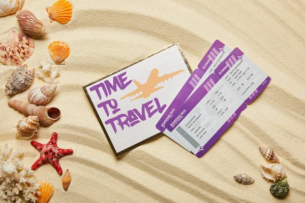 Top view of card with time to travel letting near air tickets and seashells on sandy beach — Stock Photo