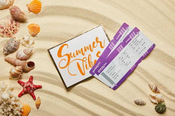 Top view of card with summer vibes letting near air tickets and seashells on sandy beach — Stock Photo